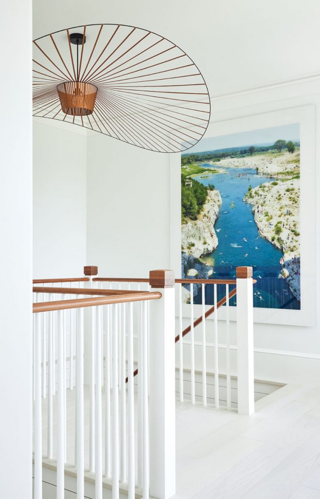A modern light fixture and a piece by Lukas Roth grace the upstairs landing. Photography by Brantley Photo