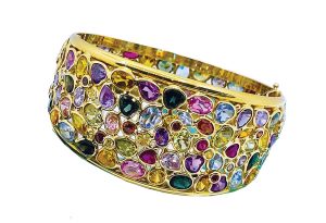 This 18-karat yellow gold cuff contains multicolored sapphires and an array of exotic gemstones that wrap around