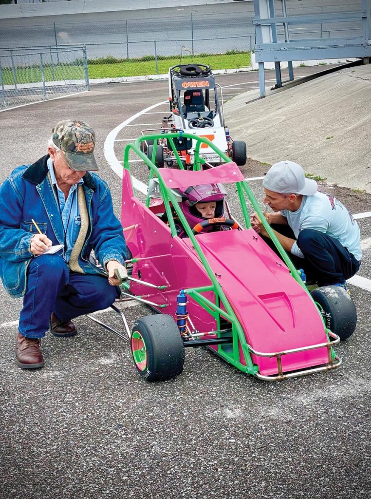 On the first test day in the new car, friend Bill Kinley checks tire temperatures as Bryant asks Lily how it’s handling