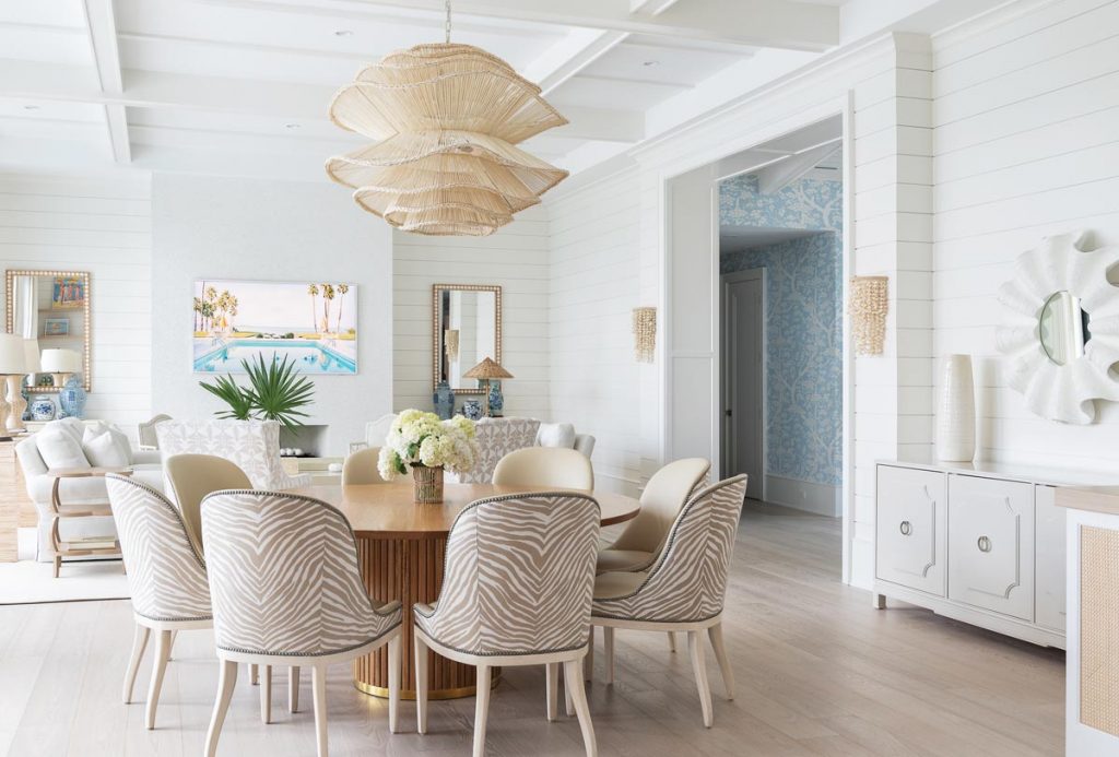 The main living area displays a floor-to-ceiling fireplace covered in mother-of-pearl tiles, and a relaxed dining area with zebra-patterned chairs. Photo by Robyn Flick