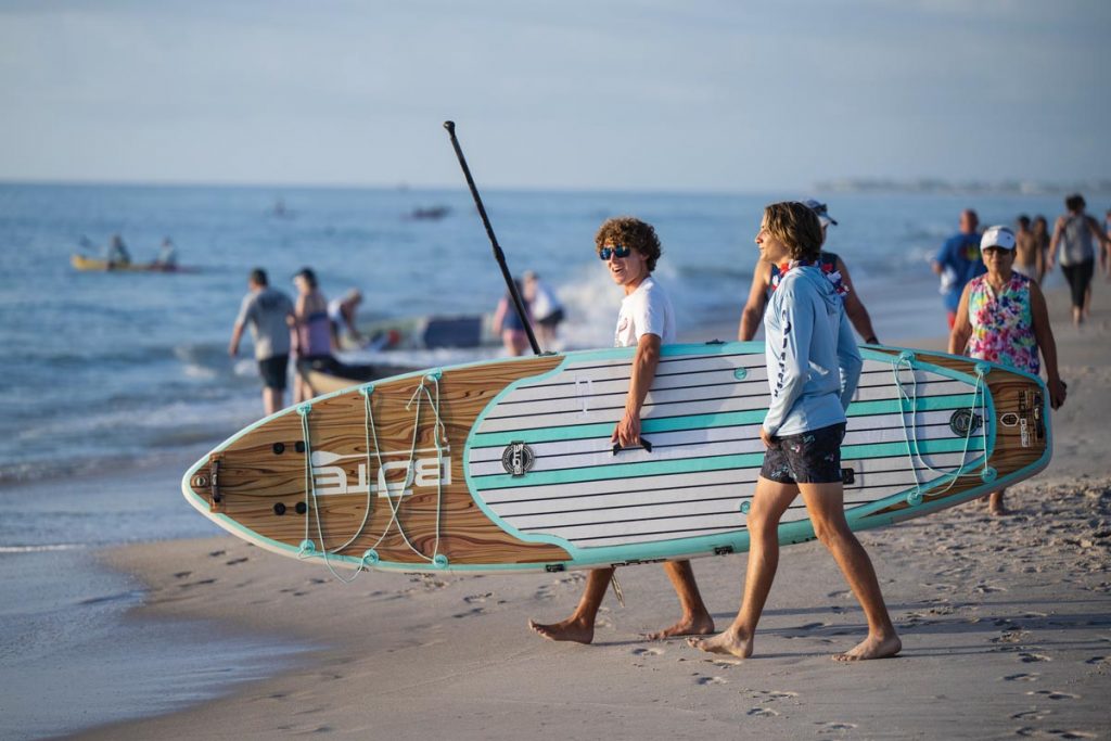 Surfboards, paddleboards, kayaks, and pool noodles are all used when people gather at the coast to Swim to the Wreck on the Fourth of July each year. Photo by Steven Martine